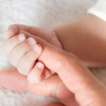 Mano de un beb&eacute; sosteniendo la mano de un adulto