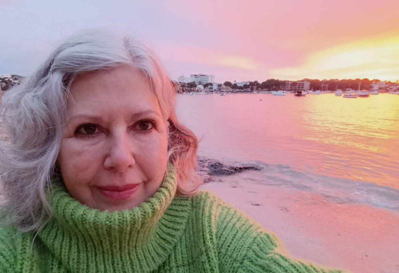 Marta Muniesa en la playa al atardecer con un su&eacute;ter verde