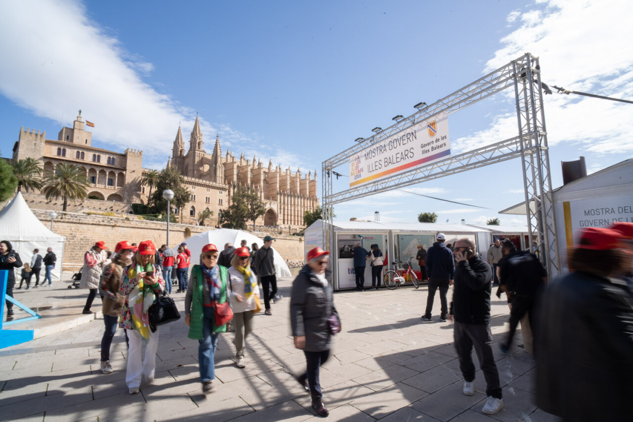 Gente caminando en la Mostra Govern en las Illes Balears con el castillo de fondo