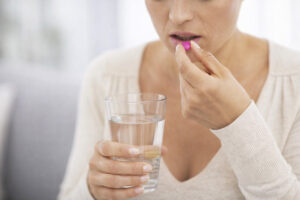 Mujer tomando una pastilla con un vaso de agua