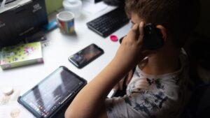Ni&ntilde;o usando una tablet mientras sostiene un tel&eacute;fono m&oacute;vil