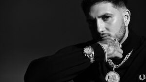 Retrato en blanco y negro de Omar Montes con joyas y mirada intensa.