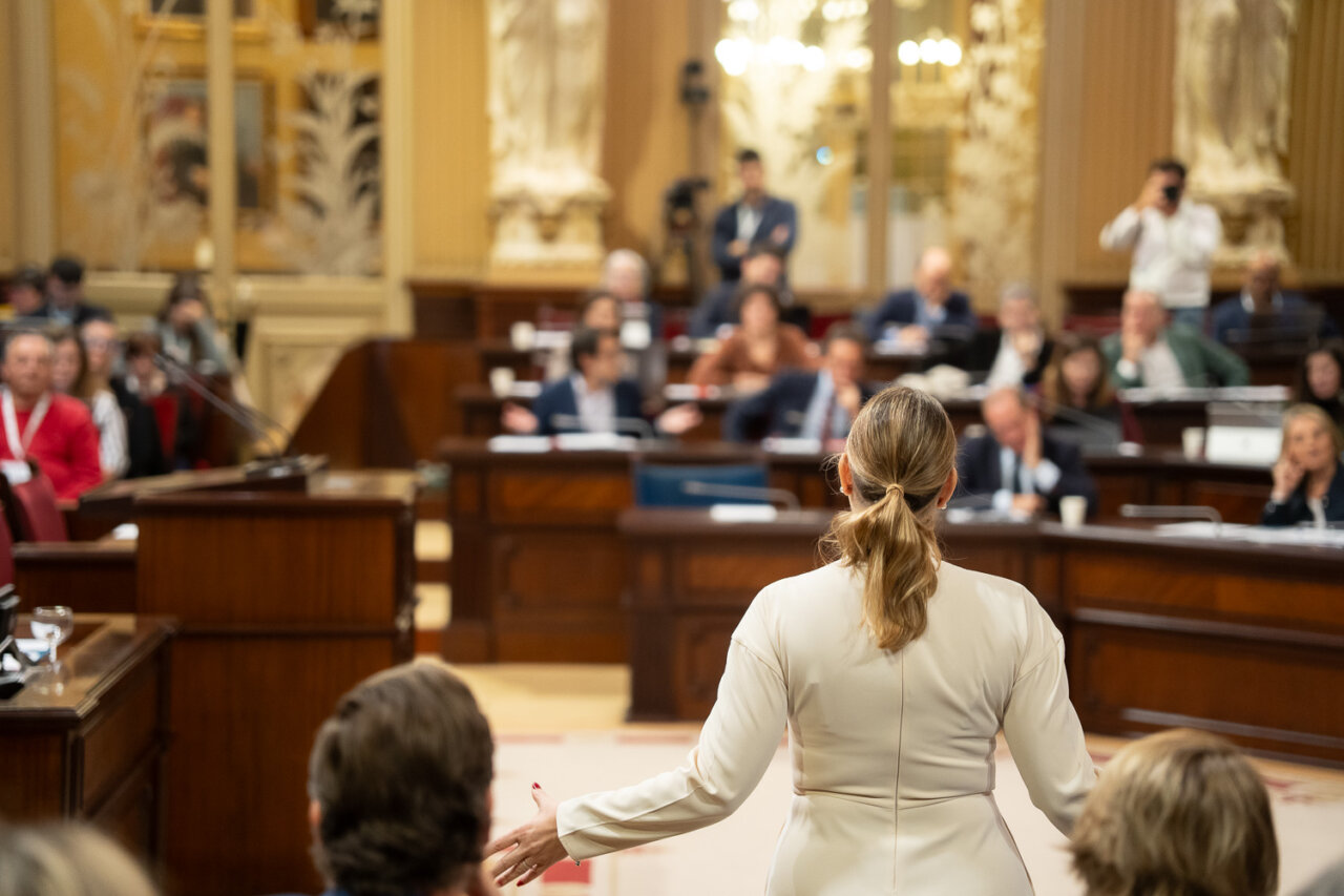 Vista de un evento en el parlamento con una oradora y audiencia