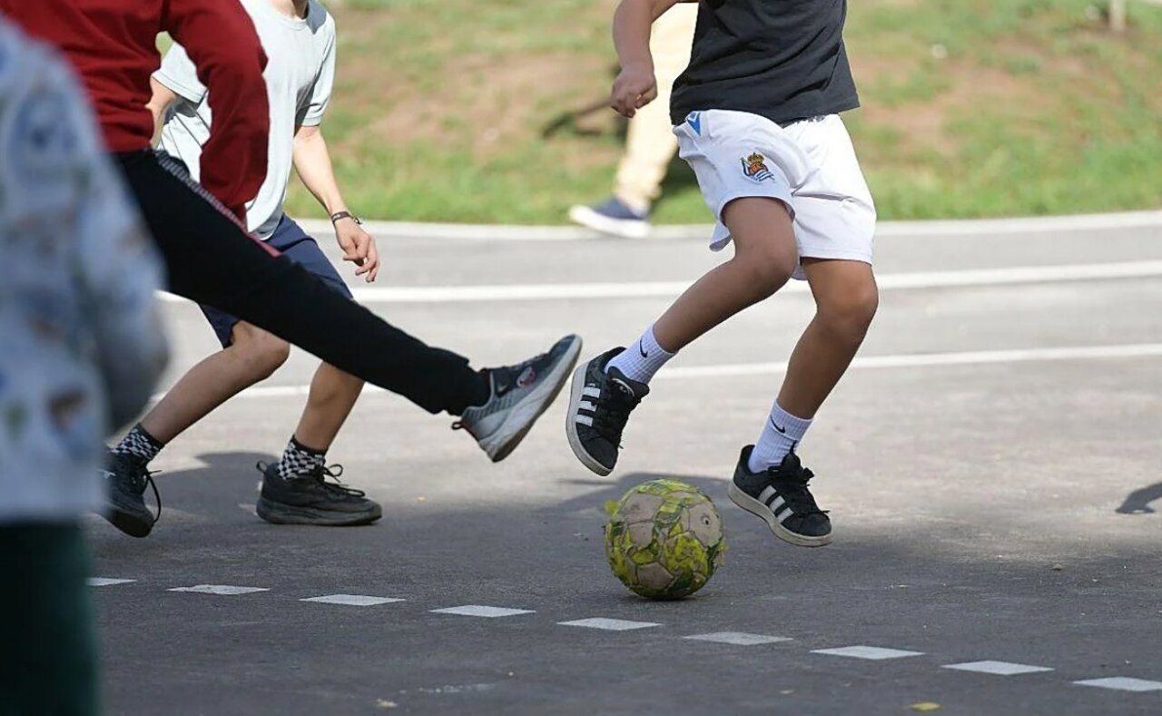 Ni&ntilde;os jugando al f&uacute;tbol en un patio escolar inclusivo