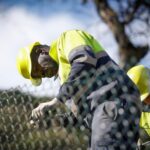 Trabajadores de la construcci&oacute;n reparando una valla en un entorno urbano
