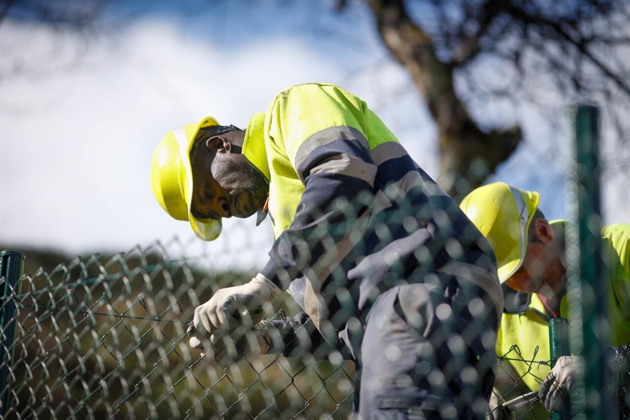 Trabajadores de la construcci&oacute;n reparando una valla en un entorno urbano