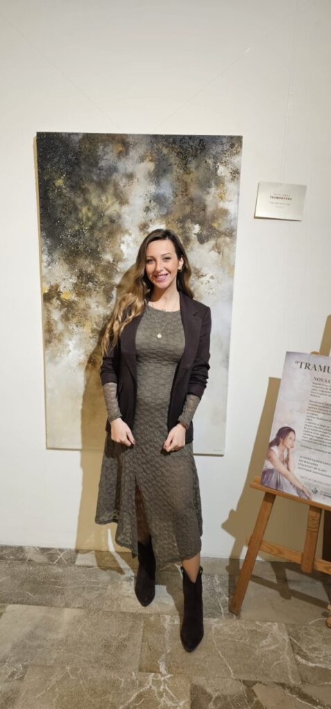 Victoria Canals en su exposici&oacute;n de arte con una obra de fondo