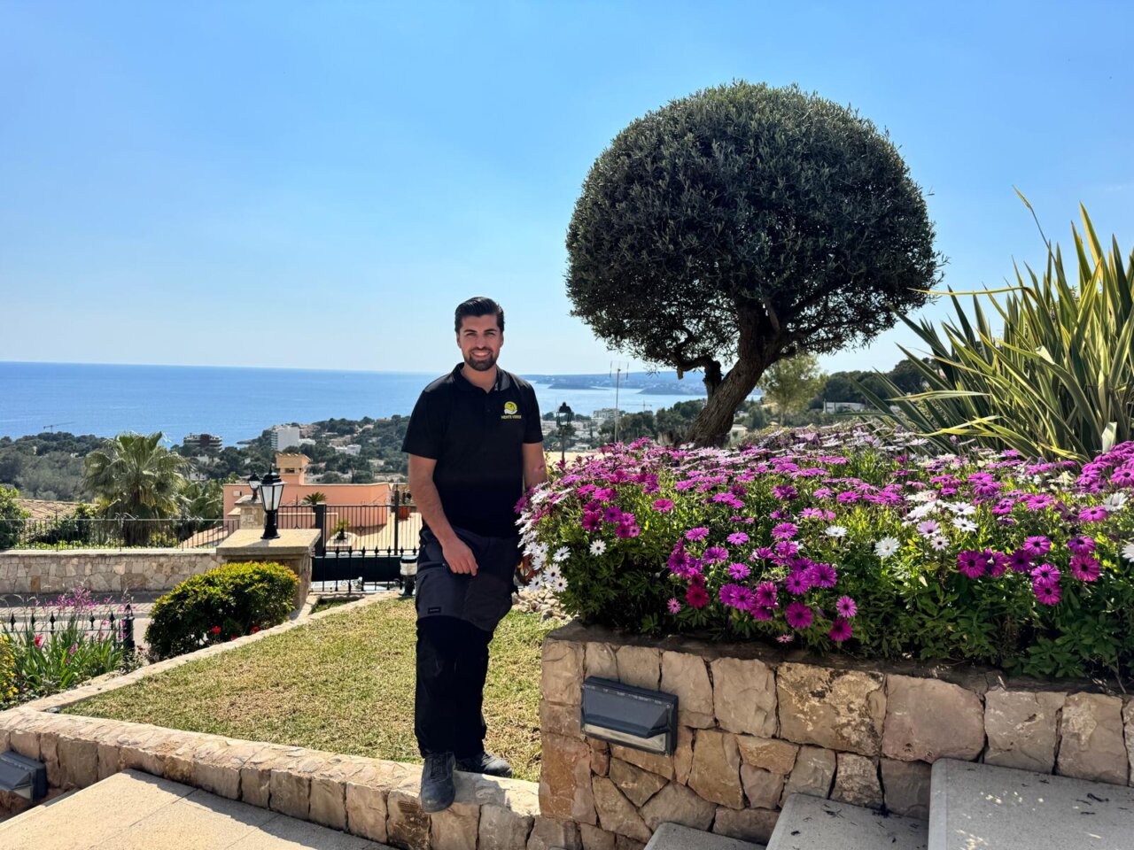 Xavi Quesada en un jard&iacute;n con flores y vista al mar en Mallorca