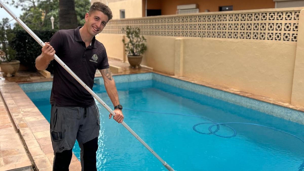 Xavi Quesada sosteniendo un palo junto a una piscina