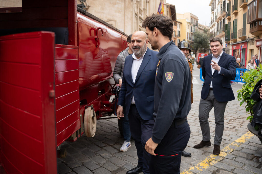 Cami&oacute;n de bomberos rojo en un evento en Palma con personas conversando.