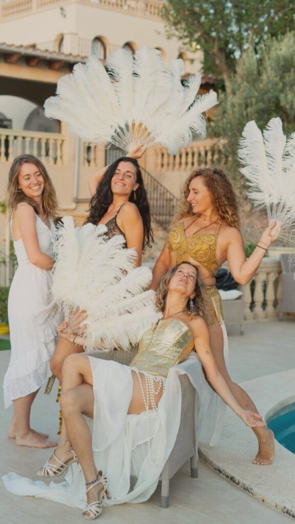 Cuatro mujeres con plumas en una celebraci&oacute;n de danza y teatro.