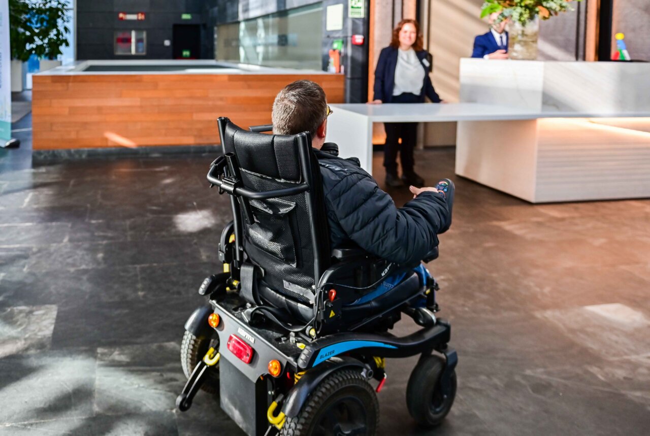 Persona en silla de ruedas en la recepci&oacute;n de un hotel moderno