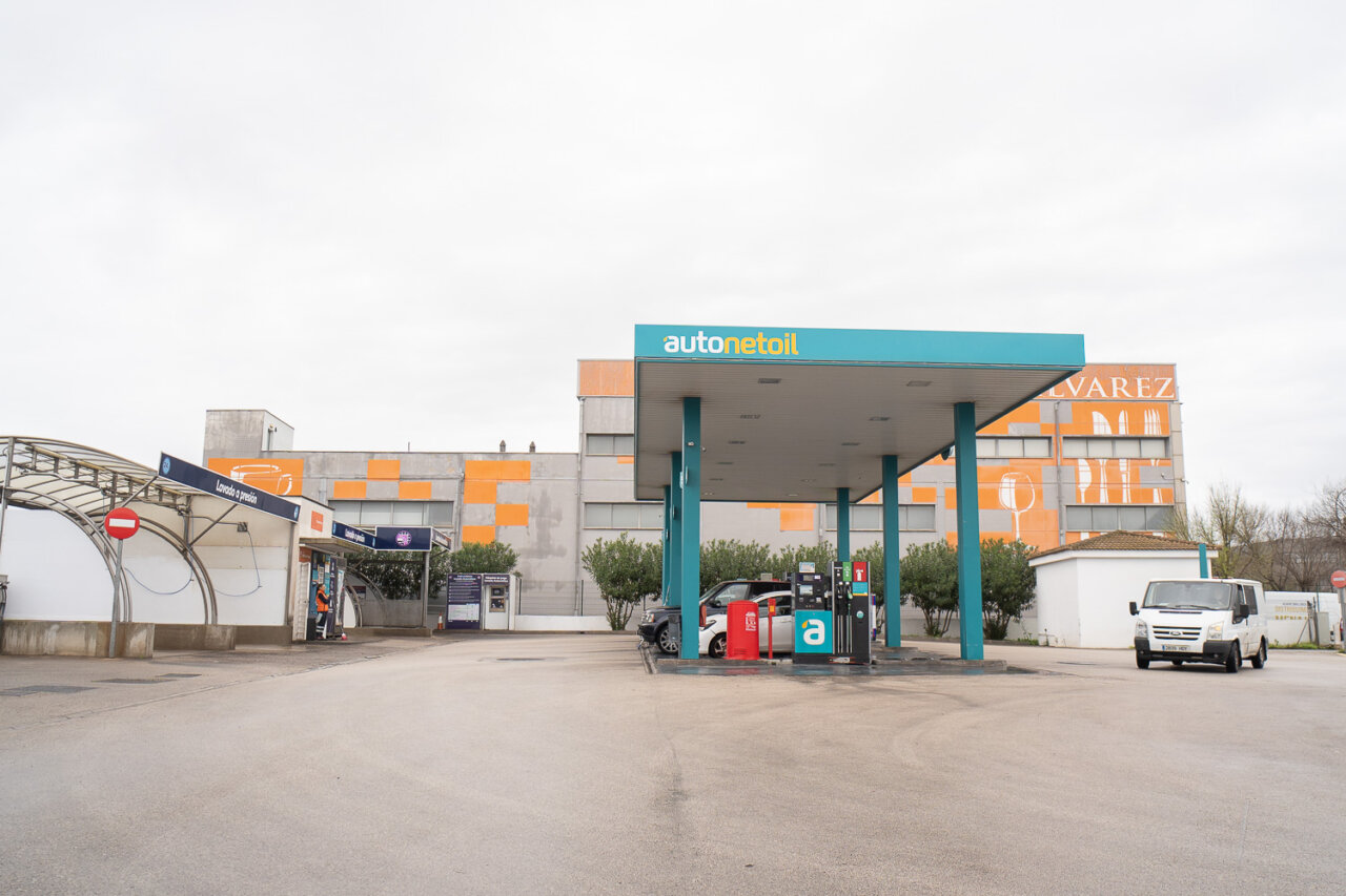 Gasolinera Low Cost con edificio de fondo y veh&iacute;culos estacionados
