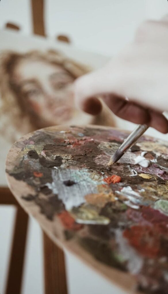 Mano sosteniendo un pincel sobre una paleta de colores mientras pinta.