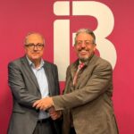 Dos hombres estrechando manos en un evento de firma de convenio