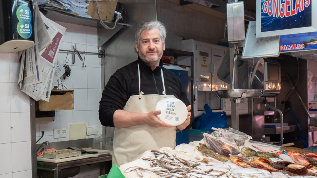 Hombre sosteniendo un plato en un mercado de pescado
