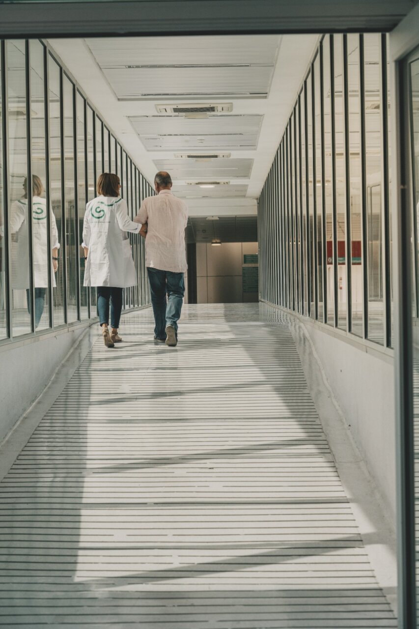 Médico acompaña a paciente en pasillo de hospital