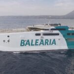 Ferry de Baleària navegando en el mar con montañas al fondo