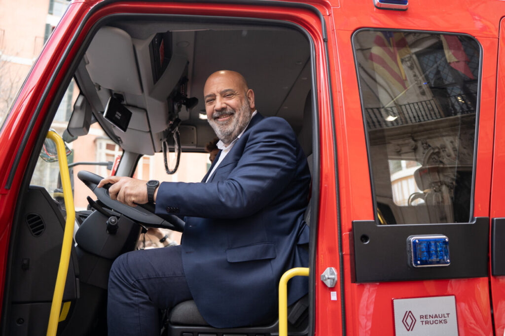 Hombre sonriente dentro de un cami&oacute;n de bomberos rojo