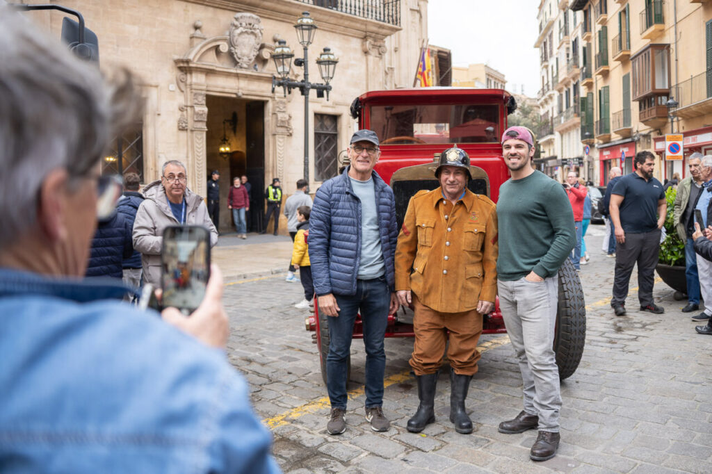 Tres personas posando junto a un cami&oacute;n de bomberos antiguo en Palma