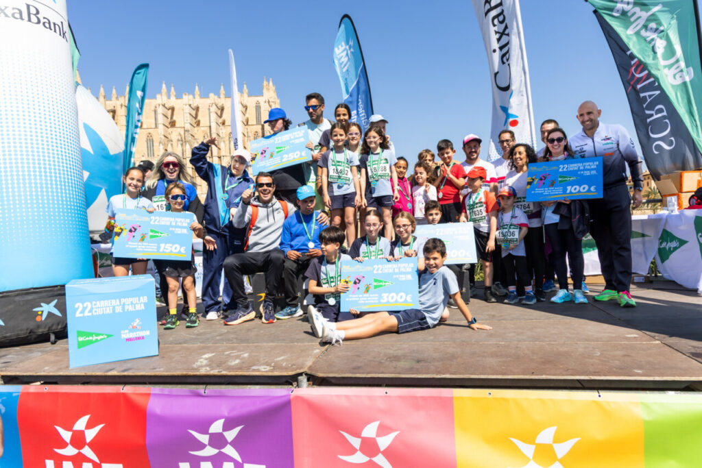Participantes de la Carrera Popular Ciutat de Palma en el podio con medallas y premios.