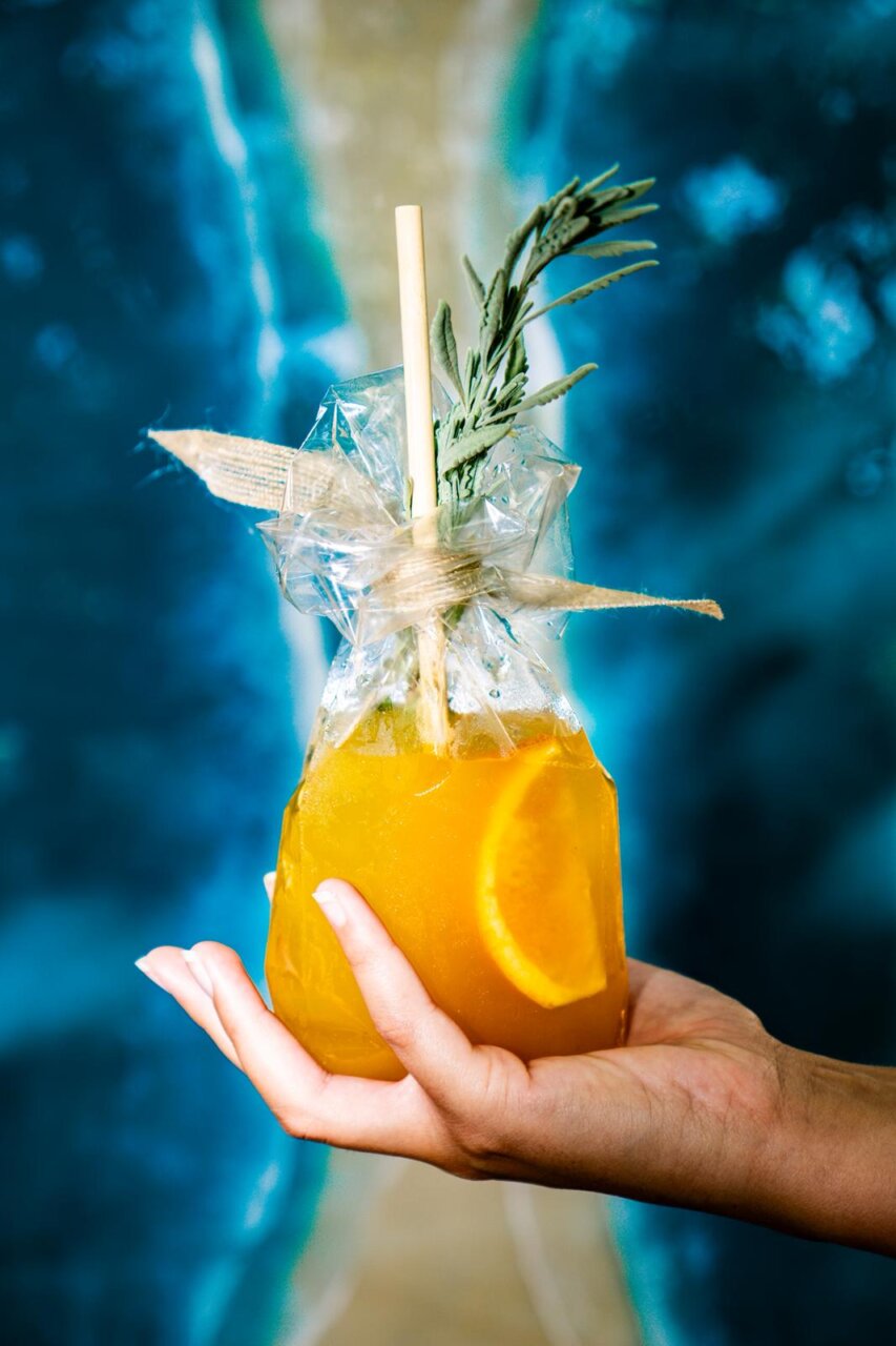 C&oacute;ctel decorado con una rodaja de naranja y hierbas