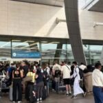 Multitud de personas en la entrada de un aeropuerto con maletas.