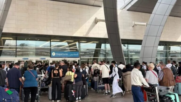 Multitud de personas en la entrada de un aeropuerto con maletas.