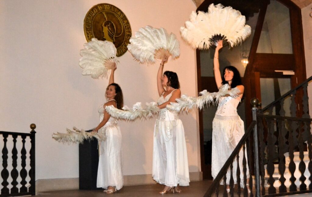 Tres bailarinas en escena con plumas blancas durante una actuaci&oacute;n de burlesque.
