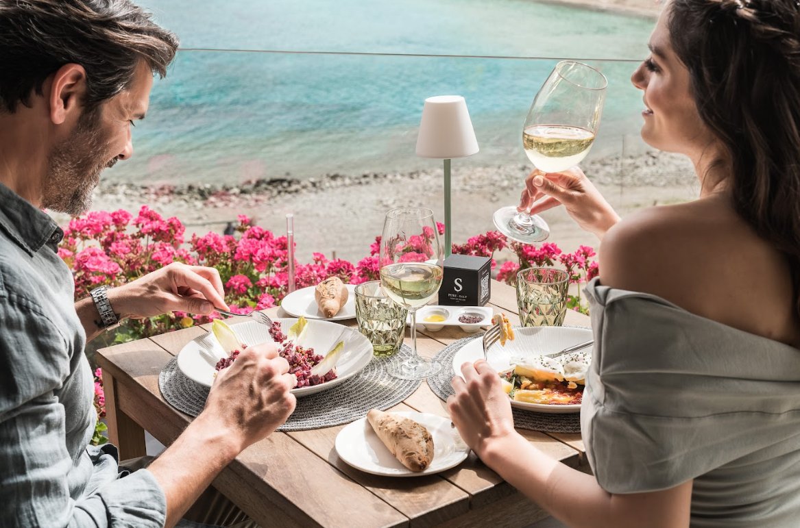 Pareja disfrutando de una comida con vistas al mar en Pure Salt