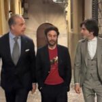 Tres hombres conversando en una calle, vestidos elegantemente.