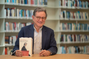 Carlos Castresana sosteniendo su libro Bajo las togas en una biblioteca