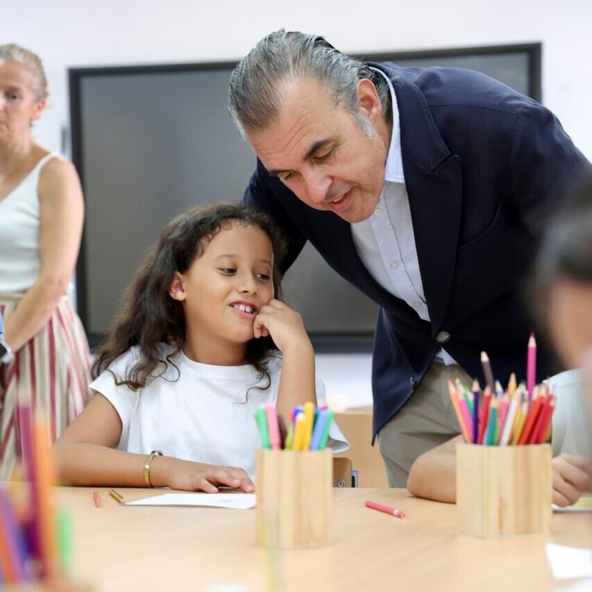 Un adulto interactuando con una ni&ntilde;a en un aula escolar