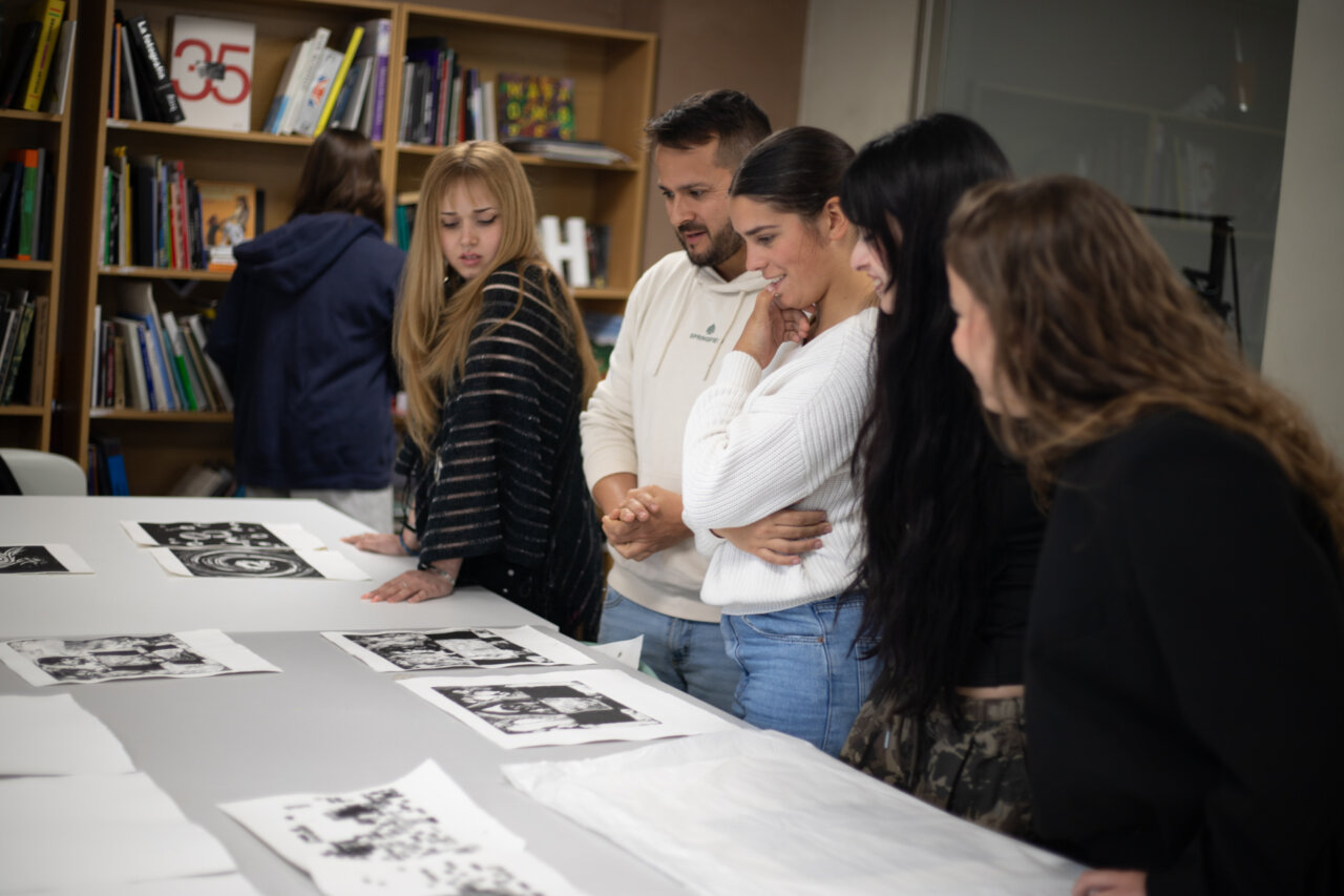 Estudiantes observando obras de arte en una mesa de trabajo