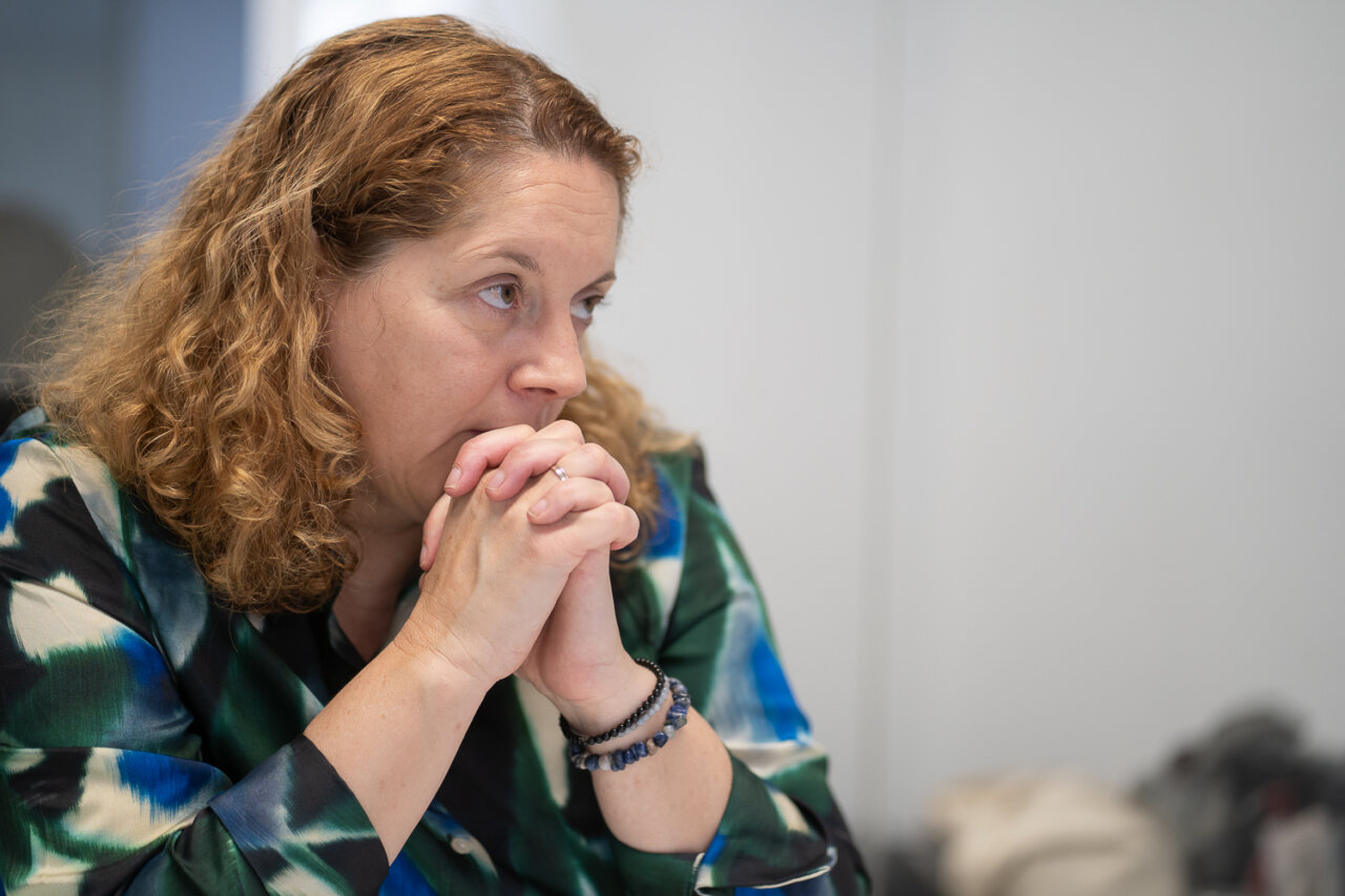 Mujer con cabello rizado pensativa en reunión de trabajo