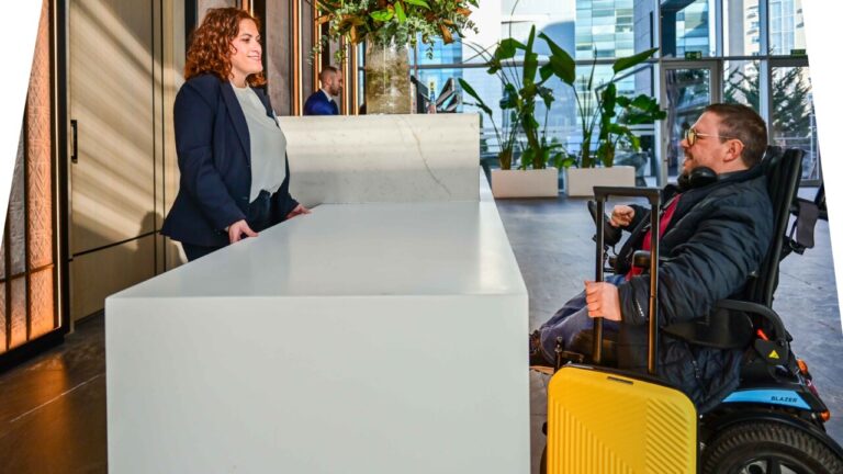 Recepción de hotel con una mujer y un hombre en silla de ruedas.