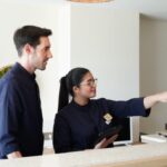 Recepcionista mostrando informaci&oacute;n en pantalla a un cliente en un hotel