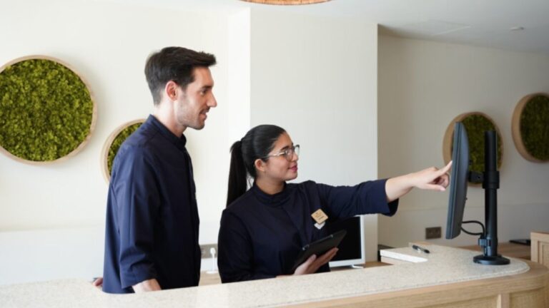 Recepcionista mostrando informaci&oacute;n en pantalla a un cliente en un hotel