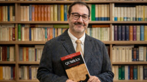 Jaime V&aacute;zquez Allegue sosteniendo el libro Qumr&aacute;n en una biblioteca