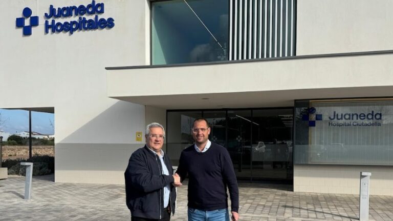 Dos hombres estrechando manos frente a Juaneda Hospitales en Menorca