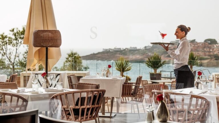 Camarera sirviendo un c&oacute;ctel en un restaurante junto al mar