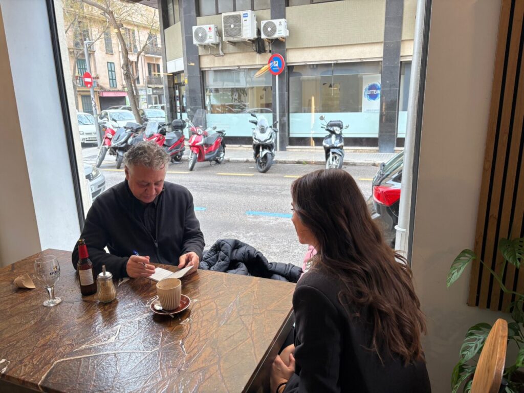 Magda Trobat en una entrevista en un caf&eacute; con un hombre escribiendo.