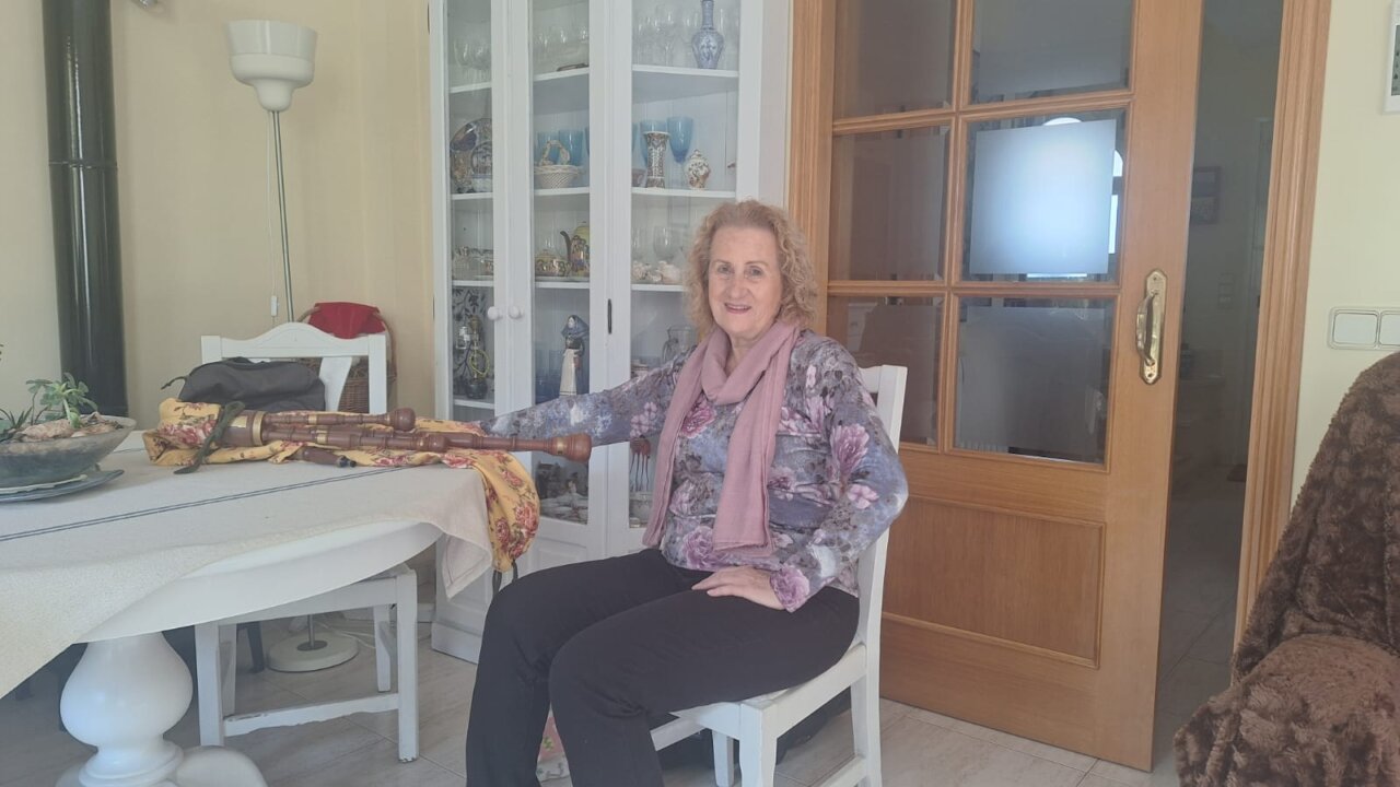 Marita Torres sentada en una silla con un instrumento musical en la mano