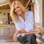 Marta Robles sonriente sosteniendo su novela Amada Carlota en un entorno acogedor.