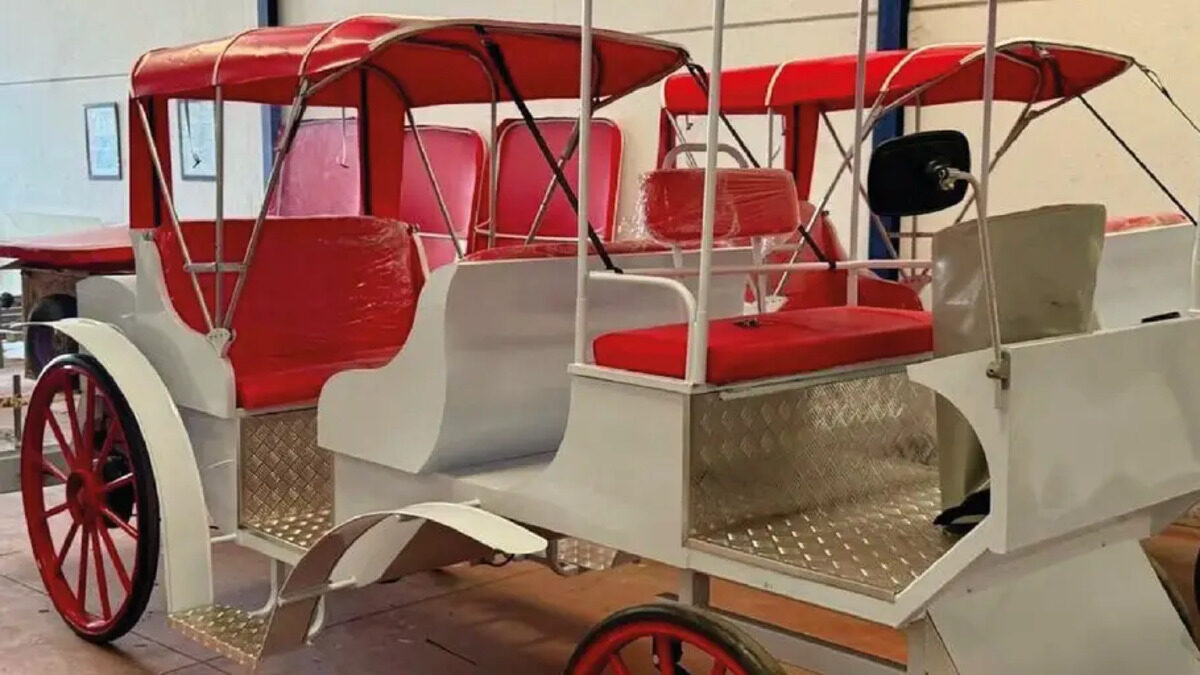 Calesa el&eacute;ctrica con asientos rojos y estructura blanca en un taller