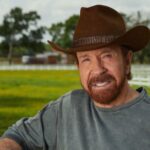 Chuck Norris posando con un sombrero en un campo verde