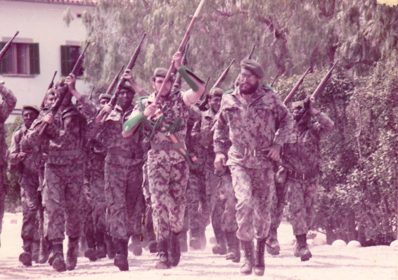 Grupo de soldados marchando con rifles en un entorno militar.