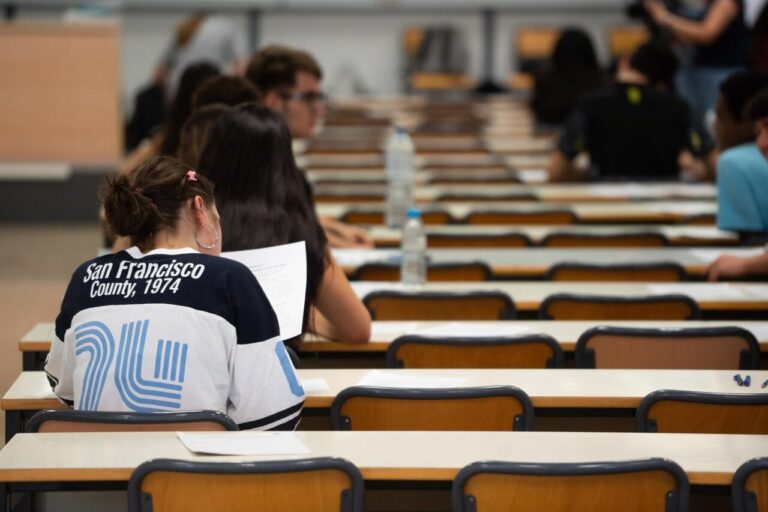 Estudiantes en un examen de la PAU en un aula con mesas y sillas