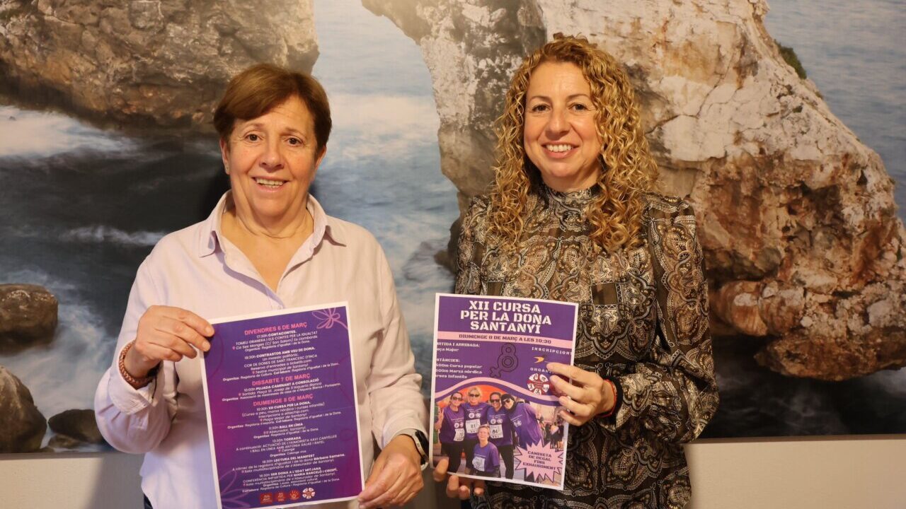 Dos mujeres sosteniendo carteles del programa del 8M en Santany&iacute;