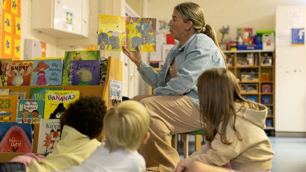 Educadora leyendo un libro a ni&ntilde;os en un entorno educativo